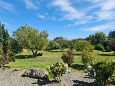 a garden with trees and rocks and a field at Duddon Villa in Millom