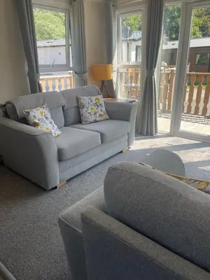 a living room with a gray couch and windows at 26 Sherwood, South Lakeland Leisure Village in Carnforth