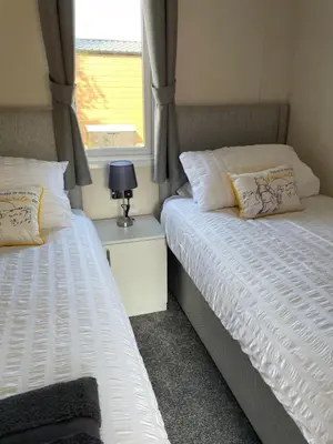 two twin beds in a room with a window at 26 Sherwood, South Lakeland Leisure Village in Carnforth