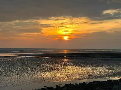 a sunset over the ocean with the sun setting at Deck Of The Bay in Heysham