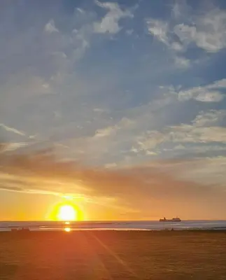 a sunset on a beach with the sun setting at Deck Of The Bay in Heysham