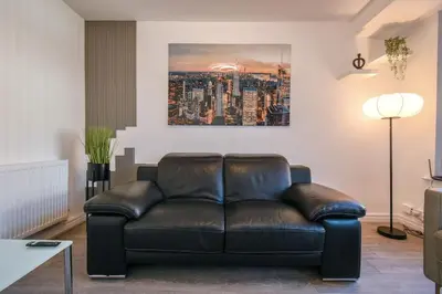 a leather couch in a living room with a painting on the wall at Modern Home: Heart Of Blackburn in Blackburn