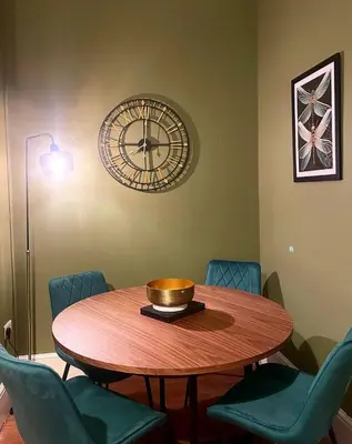 a round table with chairs and a clock on the wall at Apartment 2 West County by Prestige Properties SA in Millom