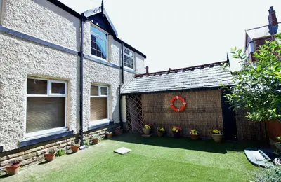 a backyard of a house with a red wreath on it at Sea Breeze Studio @ The Coach House in Saint Annes on the Sea