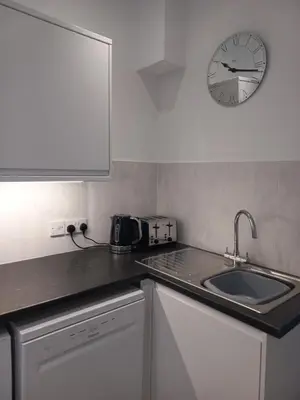 a kitchen with a sink and a clock on the wall at Sea Breeze Studio @ The Coach House in Saint Annes on the Sea