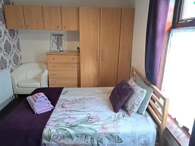 a bedroom with a bed and a dresser at Nina's Cozy Lodge in Wigan