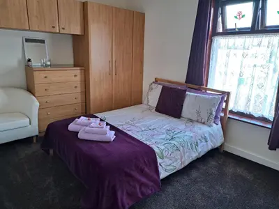a bedroom with a bed with towels on it at Nina's Cozy Lodge in Wigan