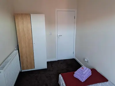 a small room with a bed and a closet at Nina's Cozy Lodge in Wigan