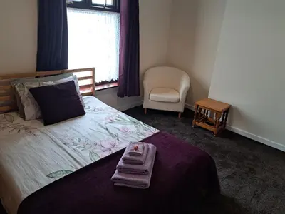 a bedroom with a bed with two towels on it at Nina's Cozy Lodge in Wigan