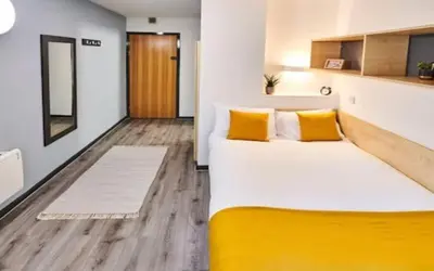 a bedroom with a large bed with yellow pillows at For Students Only - Capital Gate in Liverpool in Liverpool