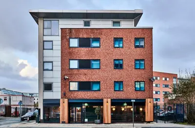 a red brick building with blue windows at For Students Only - Capital Gate in Liverpool in Liverpool