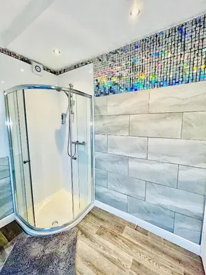 a bathroom with a shower with a tile wall at Monopoly Holiday Home in Blackpool