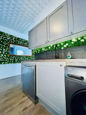 a kitchen with white cabinets and a green wall at Monopoly Holiday Home in Blackpool