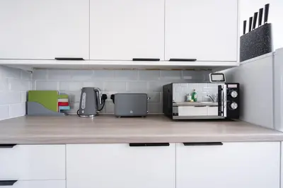 a kitchen with white cabinets and a microwave on a counter at Large 3 bedroom Liverpool Free parking in Liverpool