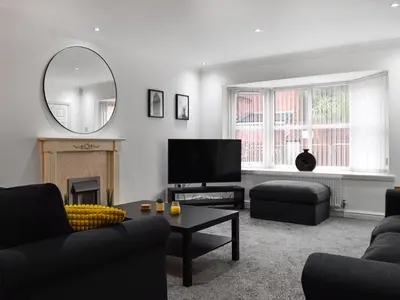a living room with a couch and a tv and a mirror at West Street House in Southport
