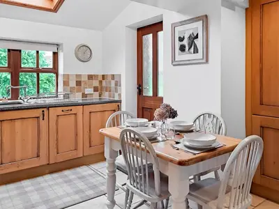 a kitchen with a wooden table with chairs and a sink at Hill View Cottage in Galgate