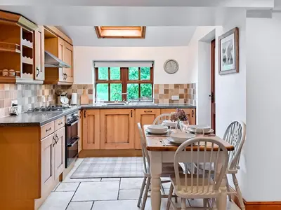 a kitchen with a wooden table and chairs and a table at Hill View Cottage in Galgate