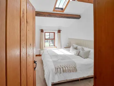 a bedroom with a white bed with a window at Hill View Cottage in Galgate