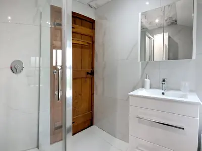 a bathroom with a sink and a shower with a mirror at Hill View Cottage in Galgate