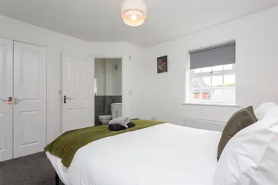 a bedroom with a large white bed and a window at Lancers Close House in Leyland
