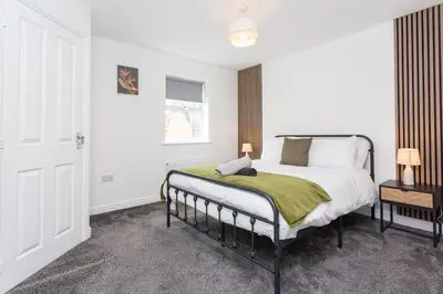 a bedroom with a bed with a green blanket on it at Lancers Close House in Leyland
