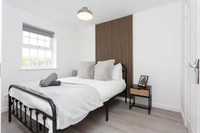 a bedroom with a bed with white sheets and a window at Lancers Close House in Leyland