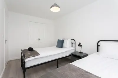 a white bedroom with two beds and a lamp at Lancers Close House in Leyland