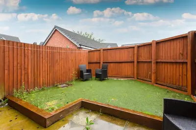 a backyard with a fence and two chairs at Lancers Close House in Leyland