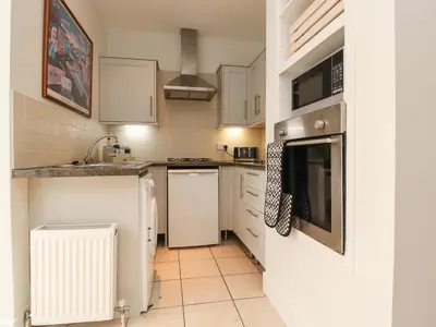a small kitchen with white cabinets and appliances at 14 Berwick Road in Lytham St Annes
