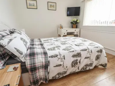 a bedroom with a bed with a blanket and a table at 14 Berwick Road in Lytham St Annes