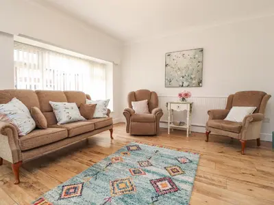 a living room with a couch and two chairs and a rug at 14 Berwick Road in Lytham St Annes