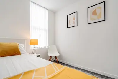 a white bedroom with a bed and a chair at Perfect Modern 4 bedroom in Liverpool in Liverpool