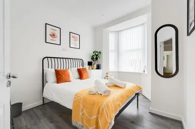 a bedroom with a bed with orange pillows and a mirror at Perfect Modern 4 bedroom in Liverpool in Liverpool