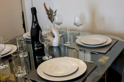 a glass table with white plates and wine glasses at Stunning 2 Bed Apartment U6 - Sleeps 8 in Liverpool