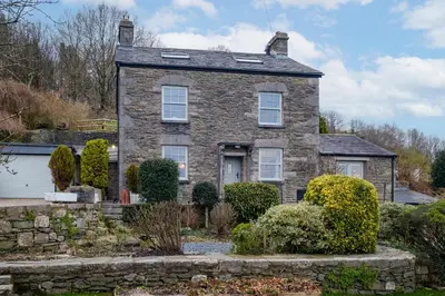 an old stone house with a stone wall at Sunny Brae in Grange Over Sands