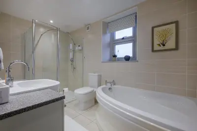 a bathroom with a tub and a toilet and a sink at Sunny Brae in Grange Over Sands