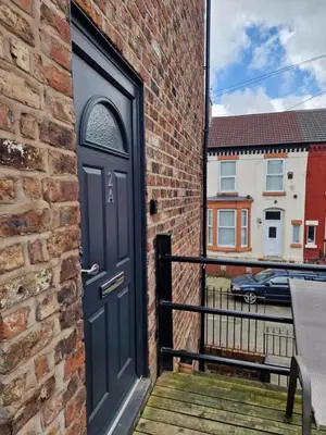 a black door on a brick building with a balcony at Beautiful Double Bedroom in Liverpool