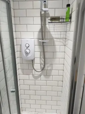 a white tiled bathroom with a shower and a toilet at Beautiful Double Bedroom in Liverpool