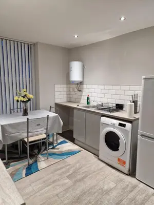 a kitchen with a washing machine and a table at Lovely Double Bedroom in Liverpool