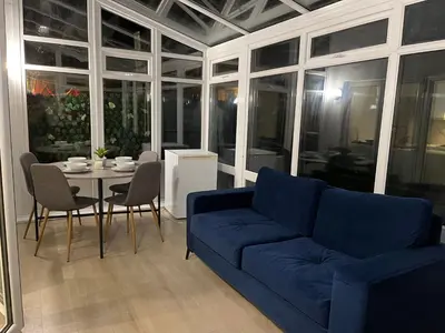 a living room with a blue couch and a table at Bright 3 bedroom house with conservatory in Birkenhead