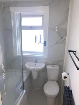 a bathroom with a toilet and a sink and a window at Bright 3 bedroom house with conservatory in Birkenhead