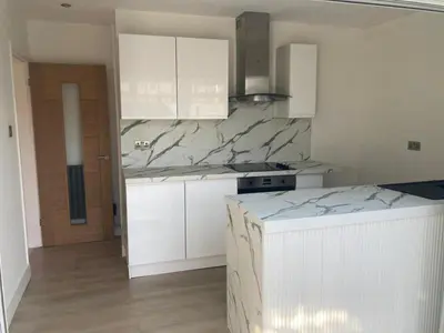 a kitchen with white cabinets and a marble counter top at Bright 3 bedroom house with conservatory in Birkenhead