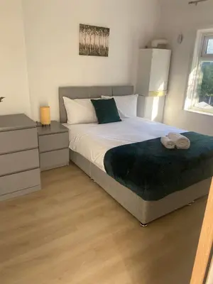 a bedroom with a large bed with a green blanket at Bright 3 bedroom house with conservatory in Birkenhead