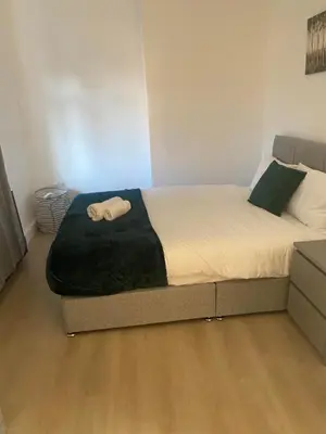 a bed with a black blanket on it in a room at Bright 3 bedroom house with conservatory in Birkenhead