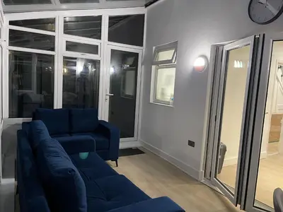 a living room with a blue couch and a clock at Bright 3 bedroom house with conservatory in Birkenhead