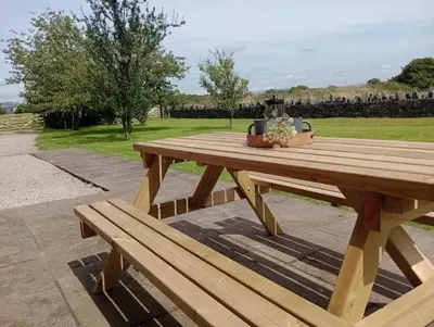 a wooden picnic table with a vase on top of it at Sunnyside Farm in Grange Over Sands