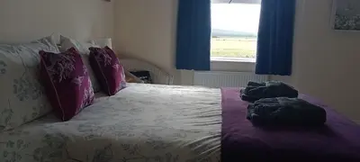 a bedroom with a bed with purple sheets and pillows at Sunnyside Farm in Grange Over Sands