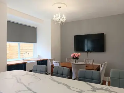 a kitchen and dining room with a table and a tv at Luxury Town House in Blackpool