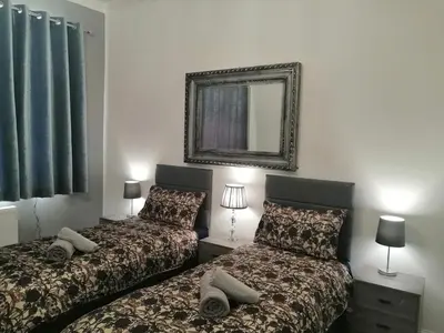 a bedroom with two beds and a mirror on the wall at Luxury Town House in Blackpool