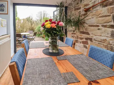 a wooden table with a vase of flowers on it at Ribble Valley Cottage in Preston